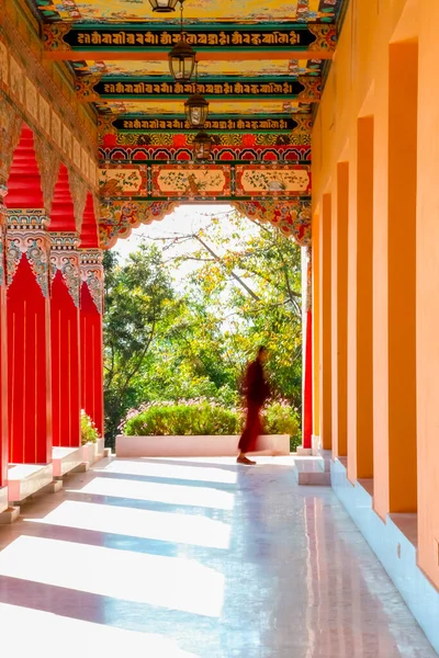 Blurred Monk Walks Past The Corridor Of A Buddhist Monastery. There Are Buddhist Scripts Written On The Ceiling.