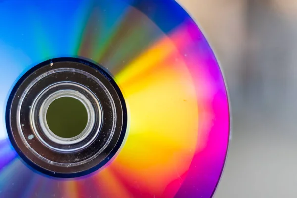Compact Disc. Holding a CD in hands. The back side of the CD reflects colorful lights. Rainbow colors.
