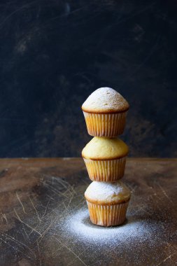 Şekerle kaplı üç muffin, koyu arkaplan.