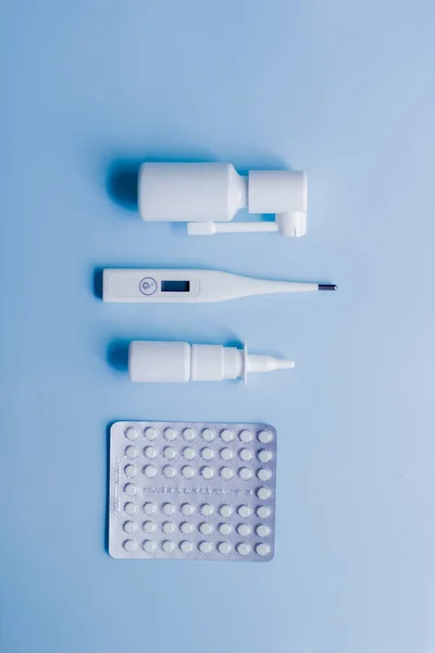 Medical supplies lie on a blue surface in the style of flat lay.