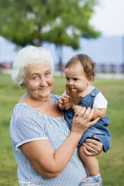 Granddaughter and grandmother embrace and walk in the autumn park