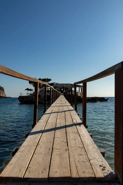 Вуден мост, ведущий через море к острову с рестораном в лагере де Мар, Мальорка, Испания — стоковое фото