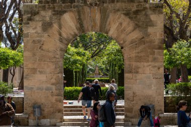 Palma, Mallorca, İspanya - 13 Nisan 2019: Güneşli bir günde Katedral de Palma 'nın arkasındaki bahçelerde yürüyen turistler
