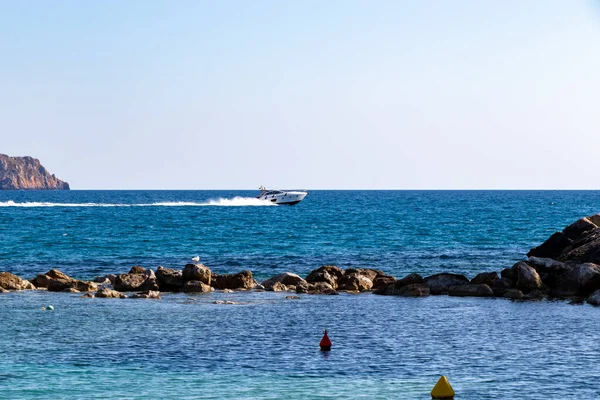 Моторная лодка между скалами, скалами, островом и морской водой во время заката с точки зрения шапки андриксола в Кэмп-де-Мар, остров Майорка, Испания — стоковое фото
