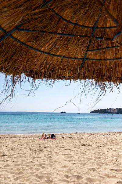 Mulheres que se bronzeiam atrás de um guarda-sóis de praia na praia de Palmanova em Calvia Bol ses Taules Mallorca, espanha — Fotografia de Stock