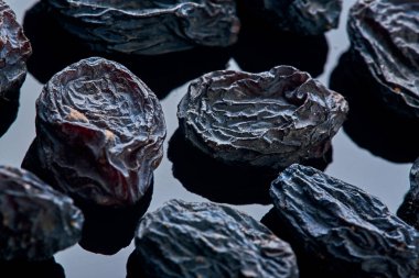 Kuru üzümler siyah cam yansıtıcı yüzeyde uzanıyorlar. Makro çekim. Geçmişi. Kurutulmuş meyve. vitamin.