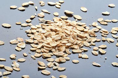 Yulaf ezmesi siyah bir yansıtıcı masanın üzerinde bir yığın halinde yatar. Bir sürü yulaf ezmesi. makro fotoğraf. arkaplan