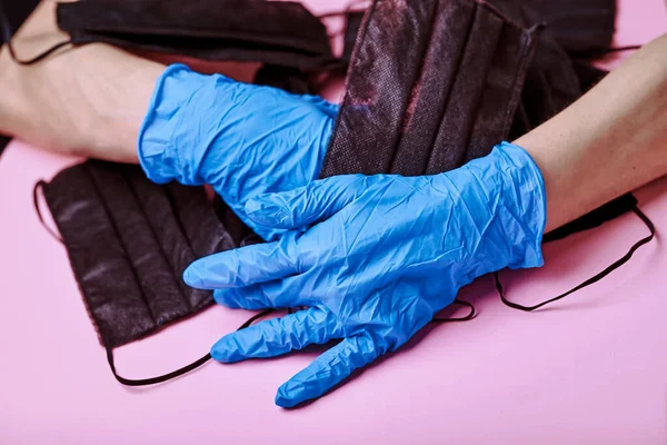 一个戴蓝色手套的女孩手里拿着一大堆口罩 粉红的桌子Covid 以保护健康 遵守卫生及检疫措施 — 图库照片