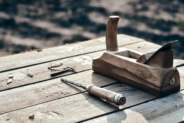wooden background. Jointer plane and chisel lies on the village table along with sawdust. Wood thread tool. solar lighting. macro photo