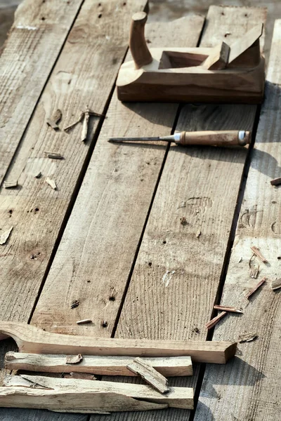 wooden background. On the village table lie dotches, sawdust, and on the background of the bit and jointer plane. vertical picture. Wood thread tool. solar lighting. macro photo