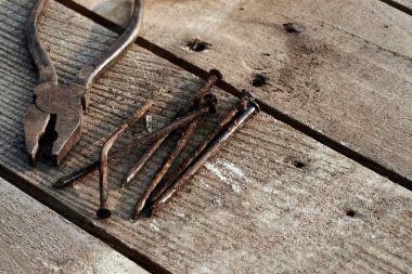 Paslı pense ve eğilmiş eski tırnaklar bir ağaç masasında yatıyor. Pas. Çatlak, çizik ev yapımı bir masa. İnşaat geçmişi. eski okul