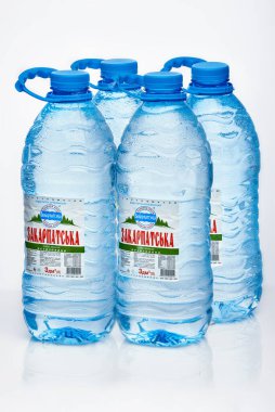 Kyiv, Ukrayna, 04.04.2020: dört büyük sulu Zakarpatska maden suyu şişesi beyaz arka planda yansımalı damlalar. Stüdyo fotoğrafı makro