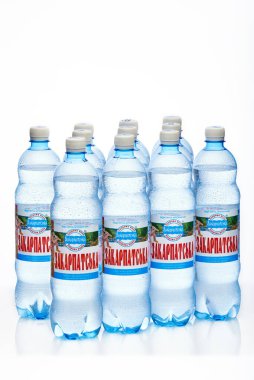 Ukrayna 'nın Kyiv kenti, 04.04.2020: 11 sulu Zakarpatska maden suyu şişesi ve beyaz bir zemin üzerinde yansıması var. Stüdyo fotoğrafı makro.