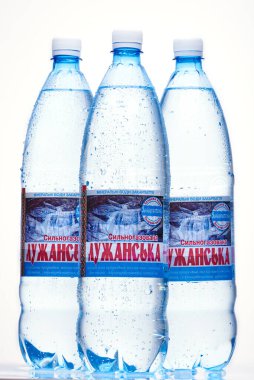 Kyiv, Ukrayna, 04.04.2020: üç sulu Luzhanska maden suyu şişesi ve beyaz arka planda yansıması var. Stüdyo fotoğrafı makro.