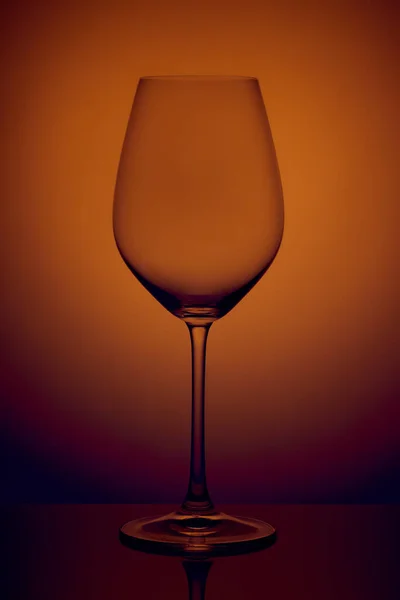 水晶玻璃站在橙色背景的反射面上 摄影棚照片 酒杯中的美丽阴影 宏观照片 — 图库照片