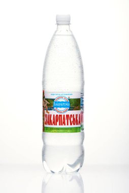 Kyiv, Ukrayna, 04.04.2020: sulu bir şişe Zakarpatska maden suyu ve beyaz arka planda yansıması olan damlalar. Stüdyo fotoğrafı makro.