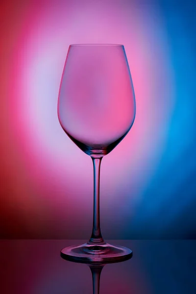水晶玻璃立在反光的表面上 呈粉红色的蓝色底色 摄影棚照片 酒杯中的美丽阴影 宏观照片 — 图库照片