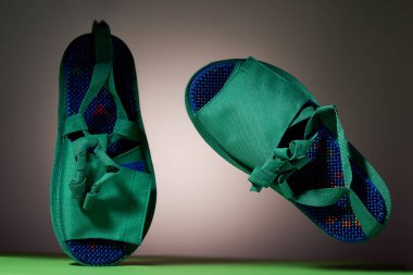 Arka planında metal iğneler olan yeşil masaj terlikleri. Rahatlama ve sağlık için. Konu ve promosyon fotoğrafçılık. Rahatlama ve sağlık için.