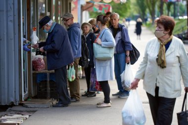 Kyiv, Ukrayna, 02.05.2020: Mağazanın girişinde tıbbi maske takan yaşlı erkekler kuyruğu. Mesafeyi korumak için. Mağazaya girmeyin. Dönüşün beklentisi. Sokak fotoğrafı. covid-19.