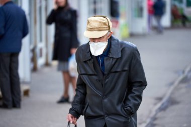 Tıbbi maske takan yaşlı bir dede elinde pastayla para istiyor. Mağazanın girişine yakın bir dilenci. Zavallı adam. Karantinaya alındı. covid-19.