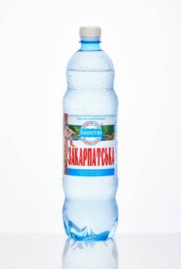 Kyiv, Ukrayna, 04.04.2020: sulu bir şişe Zakarpatska maden suyu ve beyaz arka planda yansıması olan damlalar. Stüdyo fotoğrafı makro.