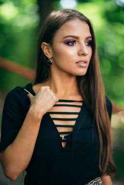 Güzel ve çekici bir kız Storna 'ya bakar, bir çanta tutar. Kahverengi gözlü, siyah ceketli. Arka planı bir kenara bırak. yarım boy portre.