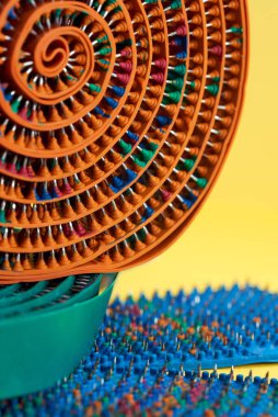 Kısmen turuncu masaj bandı, kauçuk ve dikenli, metal iğneler, bükülmüş, yeşil bantta yatıyor. Reklam, tematik ve konu çekimi. Rahatlama ve sağlık için.