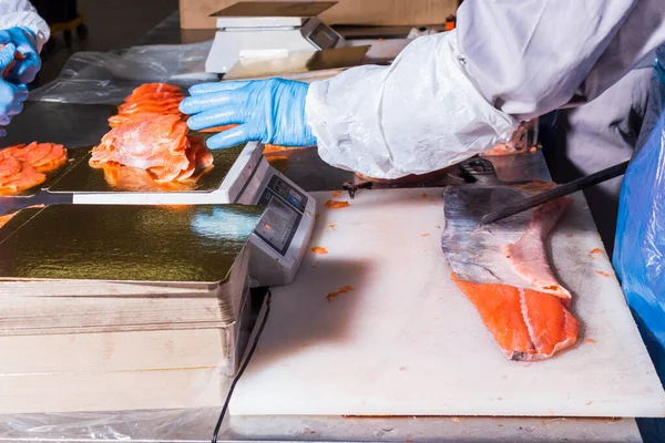 Balık üretimi. İşçi terazide balık parçaları tartıyor. Paketleme