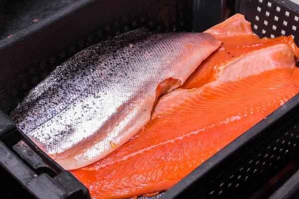 Trozos de pescado rojo con la piel fría, acostado en un recipiente negro, para su posterior procesamiento Fotos De Stock Sin Royalties Gratis