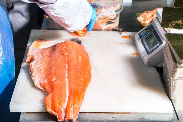 Pesce rosso si trova su un tagliere di un operaio manifatturiero per la lavorazione — Foto Stock