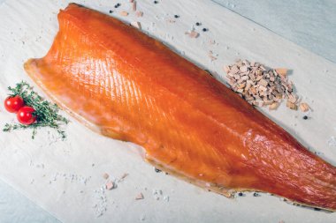 Tütsülenmiş kırmızı balık tütsülenmiş talaş ve tuzlu domateslerin yanında yatar. Durgun hayat