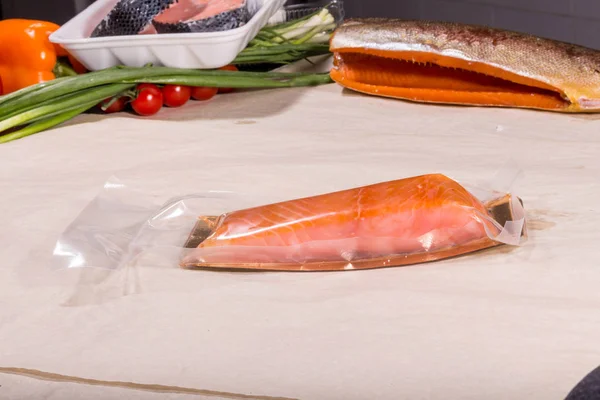 Kapalı vakumlu plastik poşetteki kırmızı balıklar meyvelerin arka planında. Tamamlanmış ürün