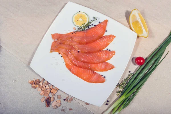 Roter Fisch in Scheiben geschnitten liegt auf einem weißen Teller. rund um Gemüse und Splitter — Stockfoto