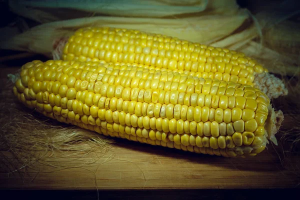 Kawałek kukurydzy obrane na drewnianej planszy na tle liści. Winieta — Zdjęcie stockowe