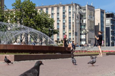 Meydandaki fıskiyede mini etekli genç kızlar fotoğraflanıyor. Yaz öğleden sonra.
