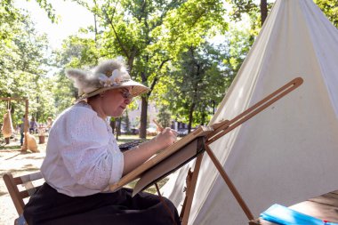 Kadın ressam, öğleden sonra doğaya suluboya bir resim çizer..