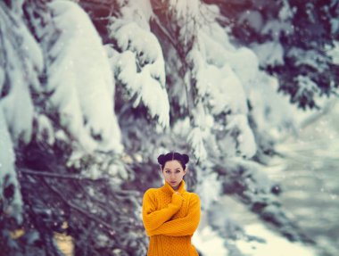 Sarı kazaklı karla kaplı bir ağacın altında mavi gözlü güzel kız. Bir peri sihirli kış ormandaki bir kız.