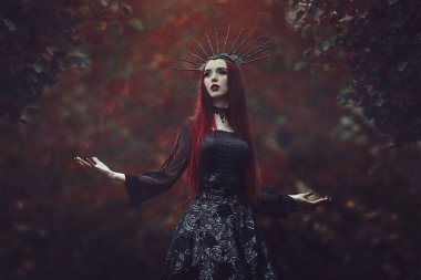 Soluk cilt ve uzun kızıl saçlı siyah bir elbise ve siyah crownk güzel bir kadınla. Vampir pençeleri ve kırmızı dudaklar ile kız cadı. Gotik bak. Cadılar Bayramı için kıyafet.
