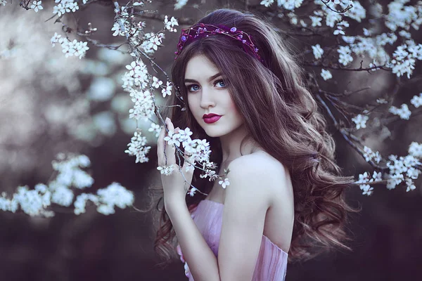 Menina romântica bonita com cabelos longos em vestido rosa perto da árvore de floração . — Fotografia de Stock