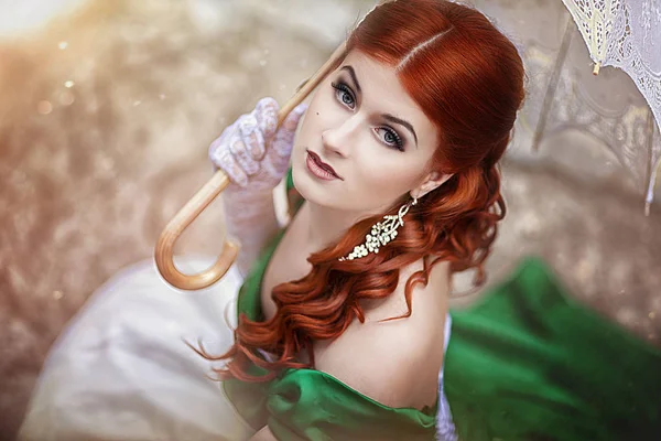 Portré egy szép fiatal vörös hajú lány egy középkori zöld ruhát egy esernyőt. Fantasy photosession. — Stock Fotó