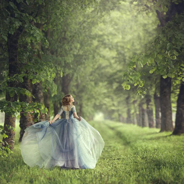 Back view of standing young beautiful blonde woman in blue dress — Stock Photo, Image