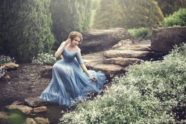 Een mooi jong meisje als Assepoester is wandelen in de tuin. — Stockfoto