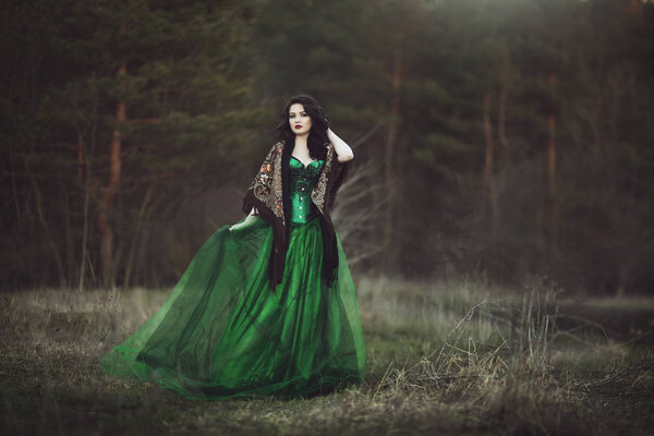 A girl in a green dress and a scarf walks through the forest. ArtPhoto