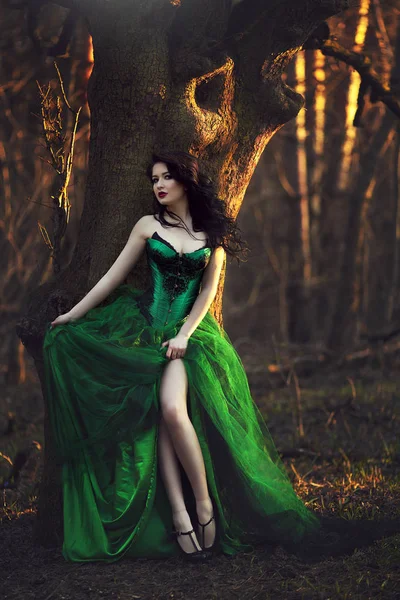 Girl in green dress posing near tree in forest. — Stock Photo, Image