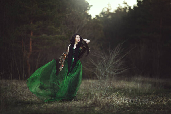 A girl in a green dress and a scarf walks through the forest. ArtPhoto