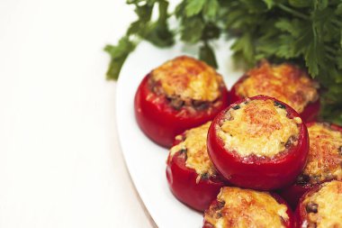 Yeşil maydanoz bir arka plan üzerinde Fırında pişmiş peynirli mantar domates dolması. Vejetaryen yemek.