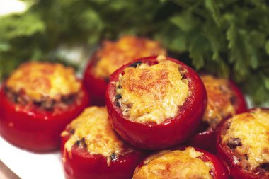 Yeşil maydanoz bir arka plan üzerinde Fırında pişmiş peynirli mantar domates dolması. Vejetaryen yemek.