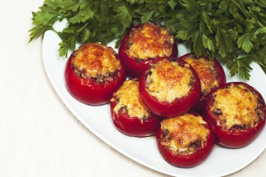 Yeşil maydanoz bir arka plan üzerinde Fırında pişmiş peynirli mantar domates dolması. Vejetaryen yemek.