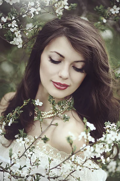 Piękna młoda dziewczyna stoi wśród kwitnących drzew. Białe kwiaty. Wiosną. Dziewczyny z włosami w białej sukni. Romans. — Zdjęcie stockowe