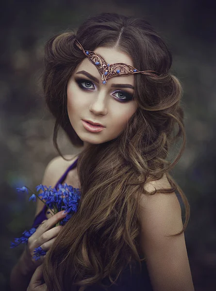 Portret van een meisje elf met lange haren en blauwe ogen, draagt een tiara met een boeket van Lentebloemen in het bos. Meisje prinses dromen. — Stockfoto